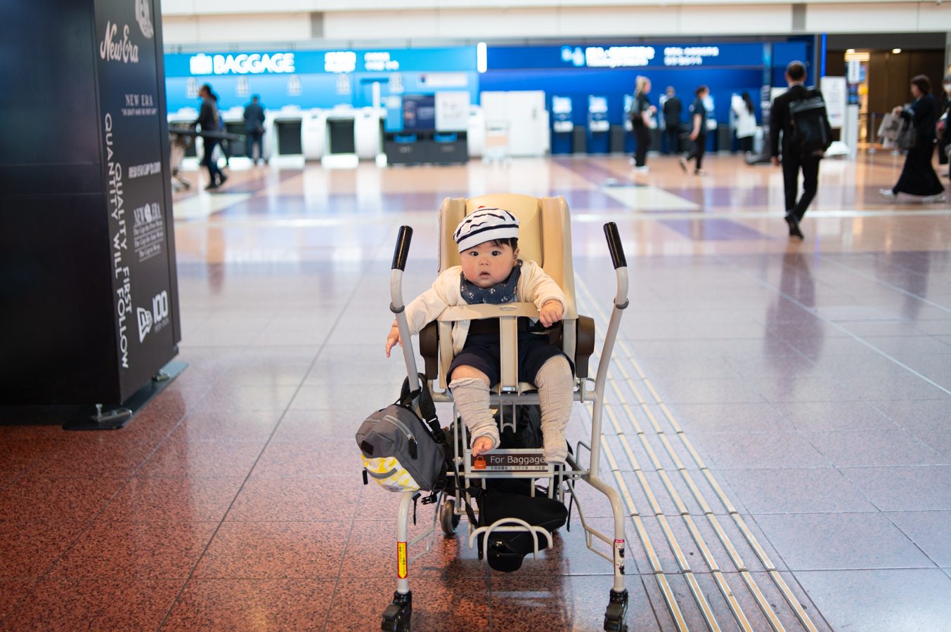 空港のバゲッジカートに乗って出発を待つ赤ちゃん