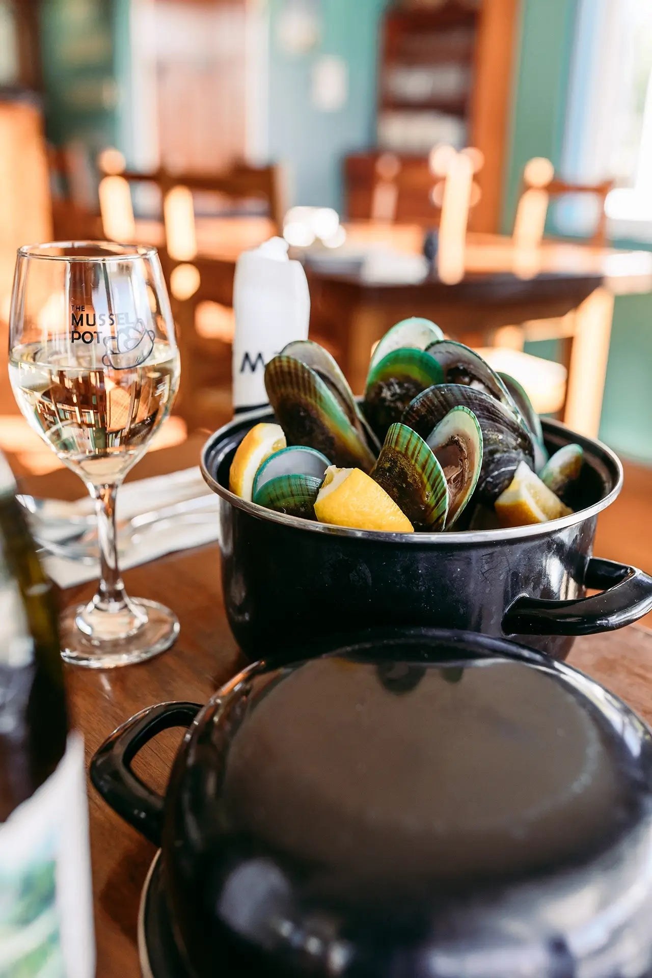 The Mussel Potで鍋に盛り付けられた、緑色の殻のムール貝とレモン