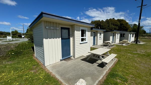 Mapua Seaside ParkのBasic Cabinsの外観。独立した入口と屋外のピクニックテーブルが並ぶ