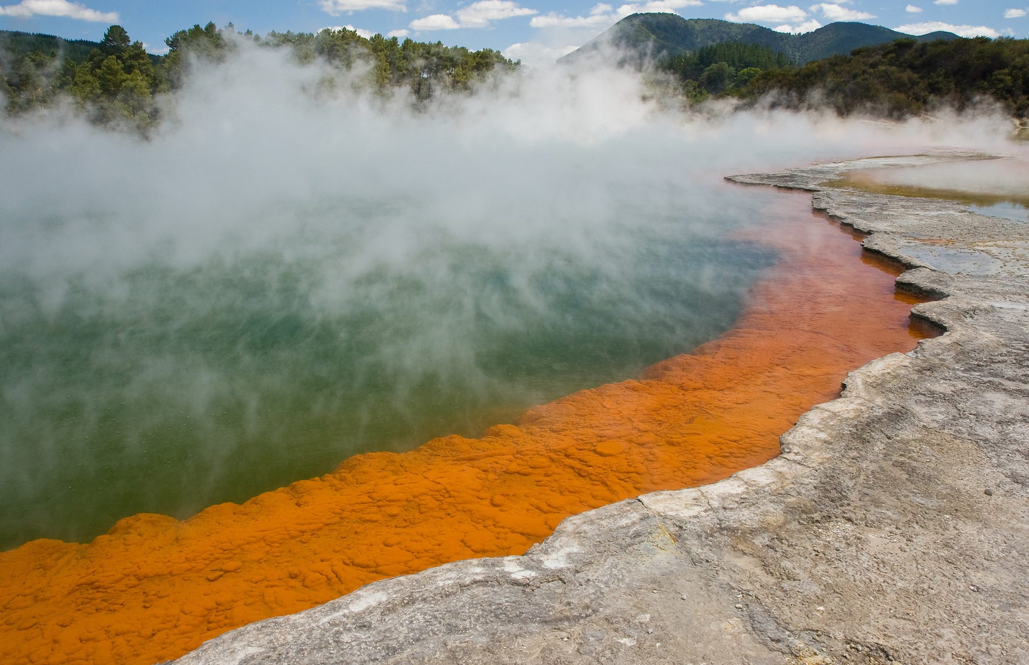 白い蒸気が流れる青緑色とオレンジ色のChampagne Pool