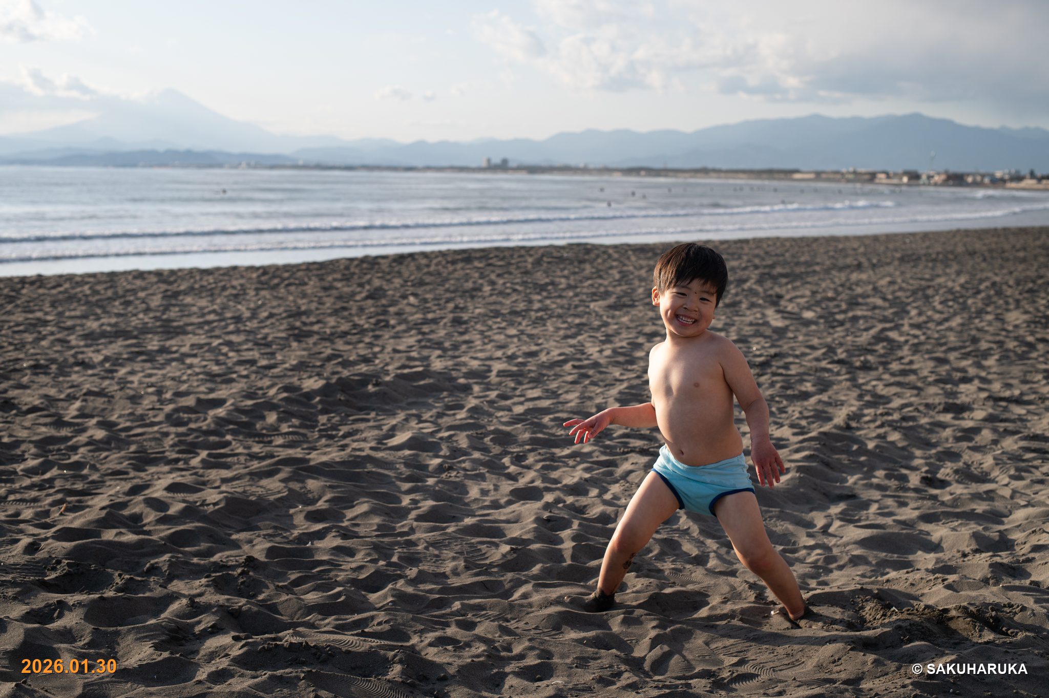 誰もいない砂浜を全力で走る水着姿の男の子
